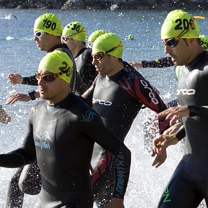 momento dell'ingresso in acqua alla partenza di una gara di triathlon, si vedono gli atleti che tutti assieme corrono verso le onde del mare